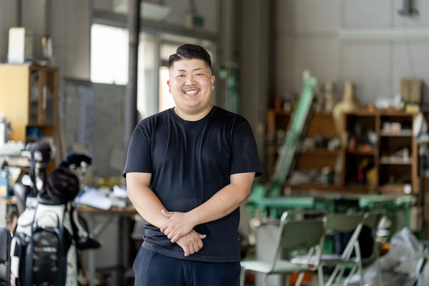 4代目 倉林尚輝が作業場で笑顔で立つ人物カット